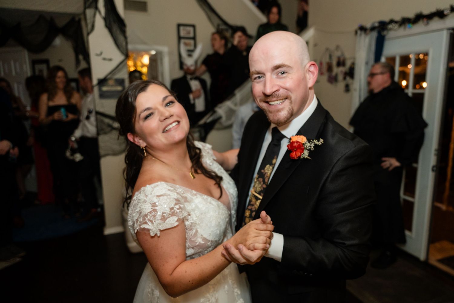A celebratory dance moment at an indoor wedding reception with Halloween decorations.