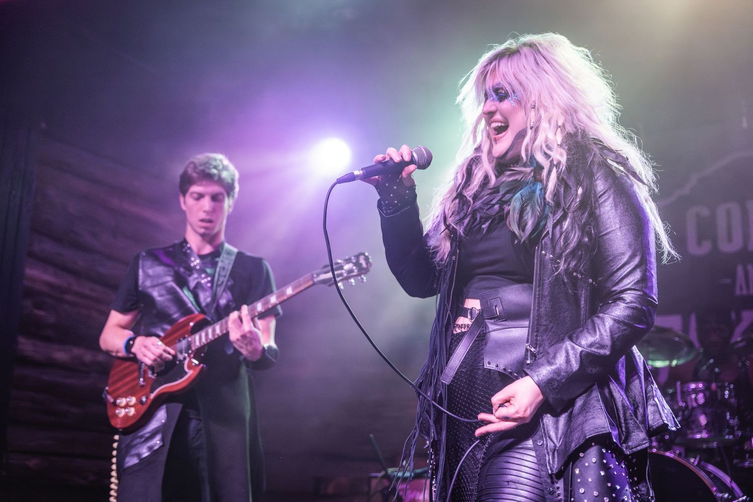 Live music performance on dimly lit stage with purple and green lighting effects.
