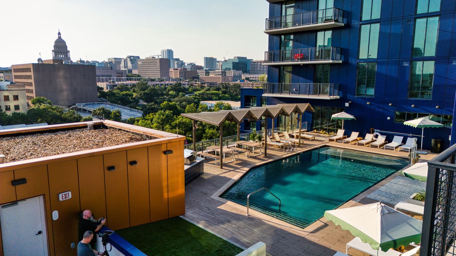 Rooftop pool deck of luxury apartment complex with downtown skyline views and lounge chairs.
