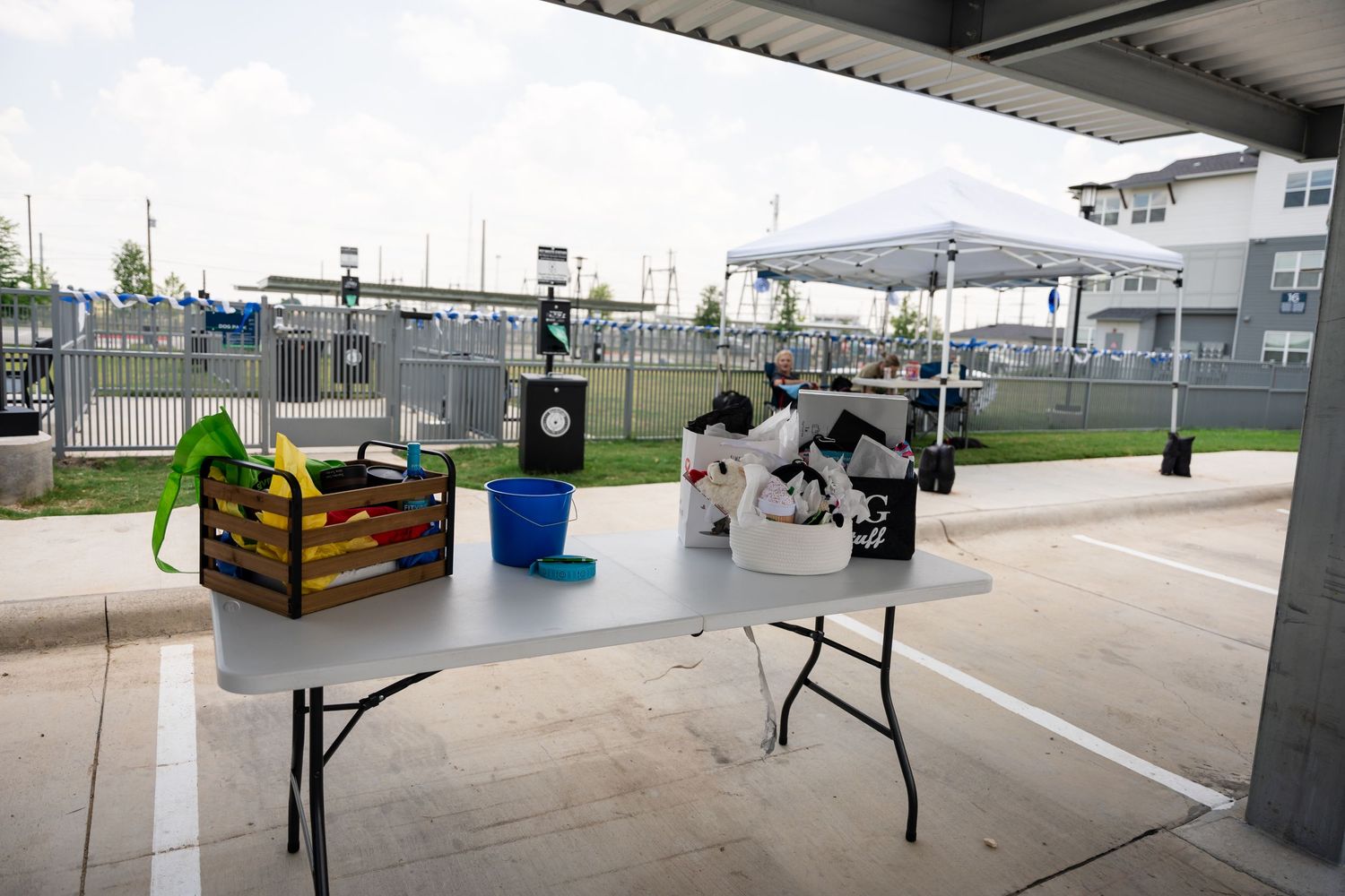 Outdoor event setup with folding tables and equipment under a covered area.