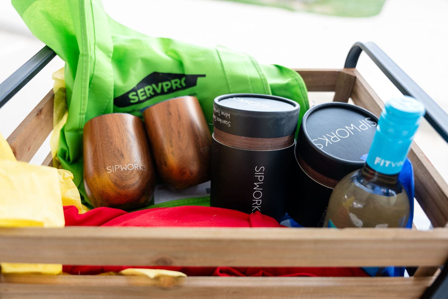 Wooden crate filled with beverages and supplies including drink bottles and mason jars.