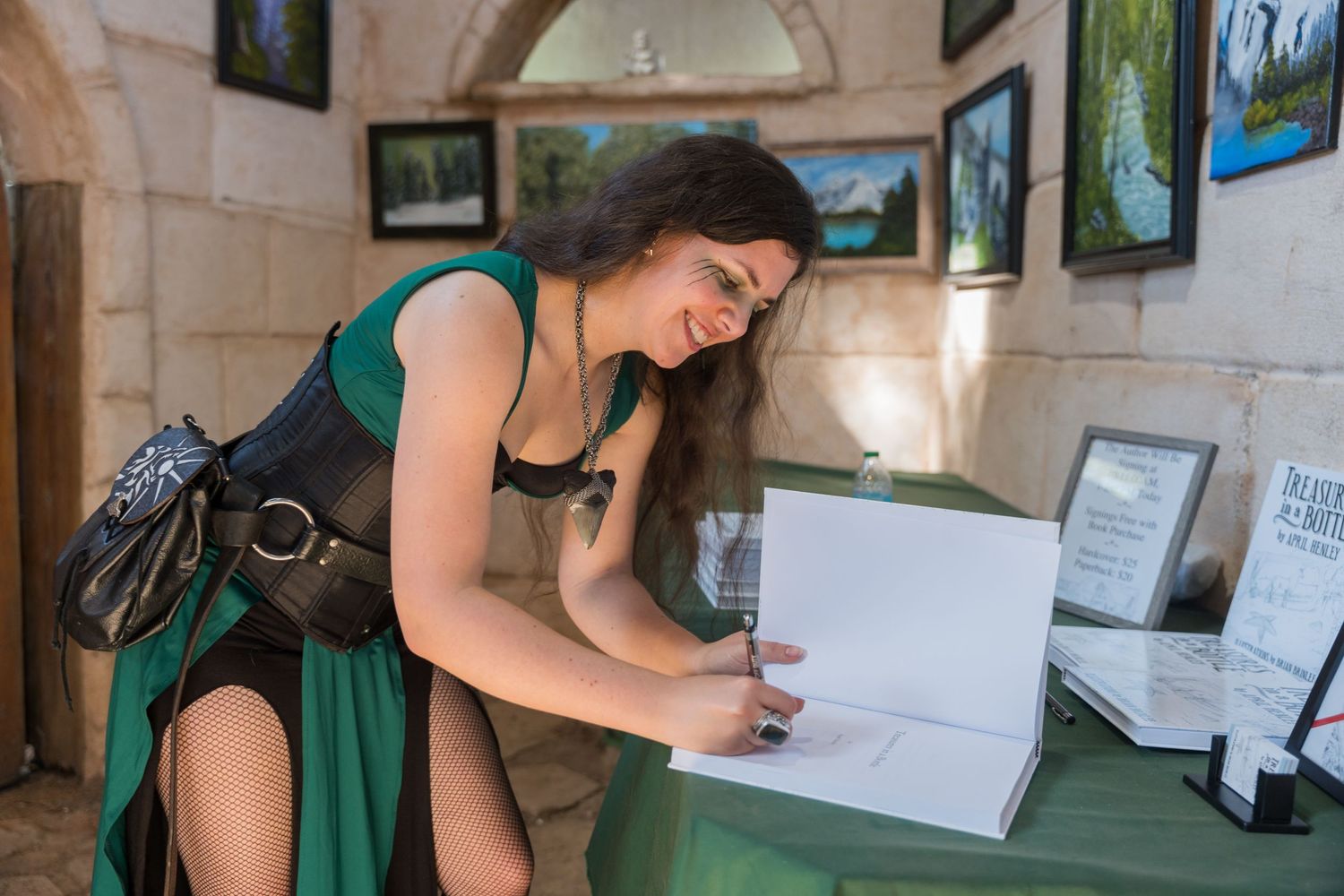 Someone in a green dress examines merchandise at an art gallery or vendor booth.