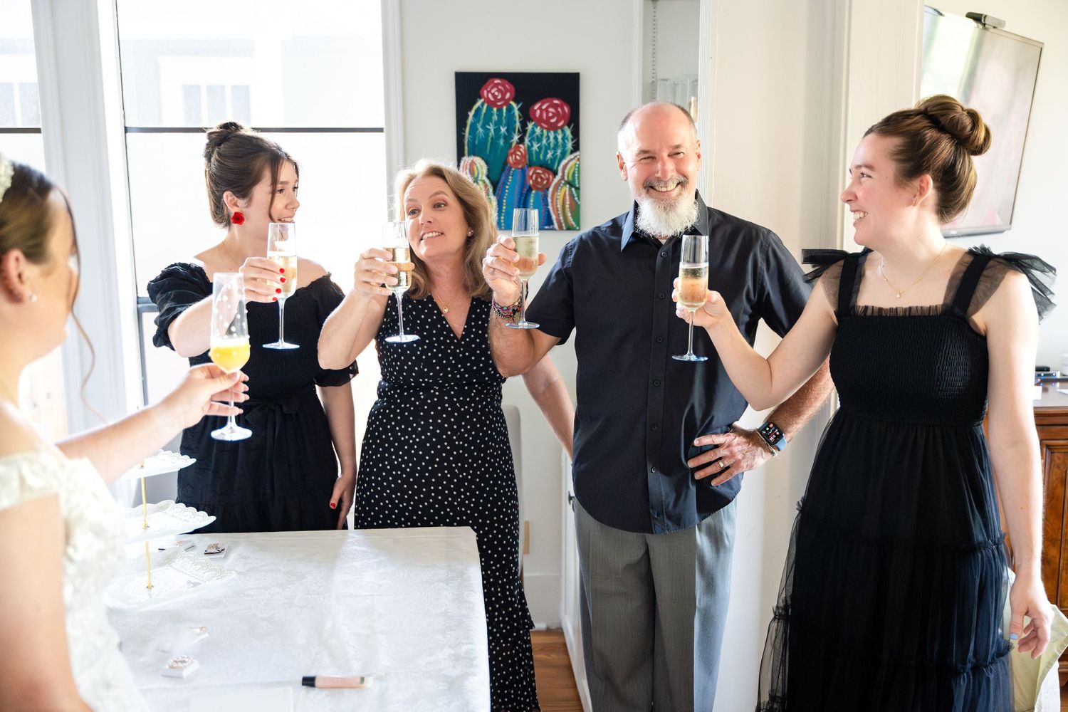 A group gathers for celebratory drinks while wearing formal black and polka dot attire.