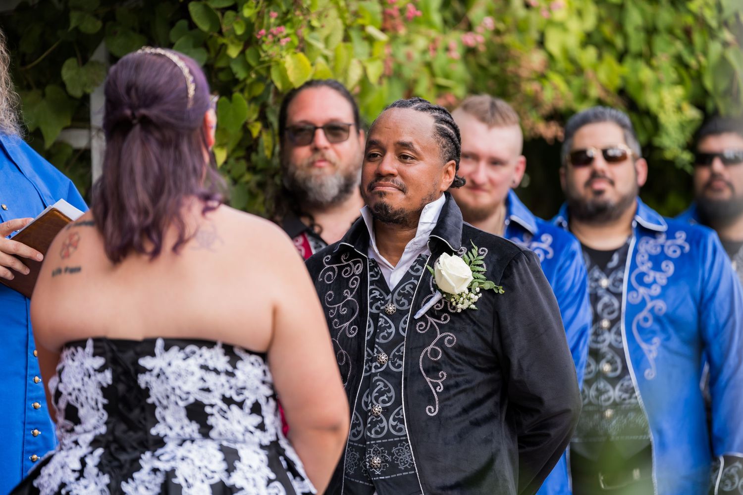 Wedding attendees gather outdoors for a ceremony with decorative attire.