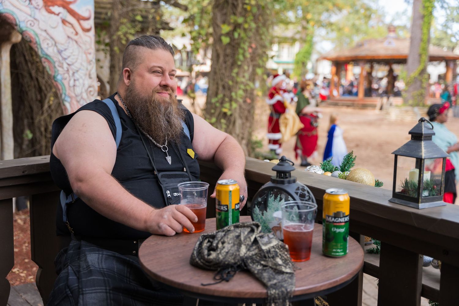 Person enjoying drinks at an outdoor tavern table during a Renaissance festival.