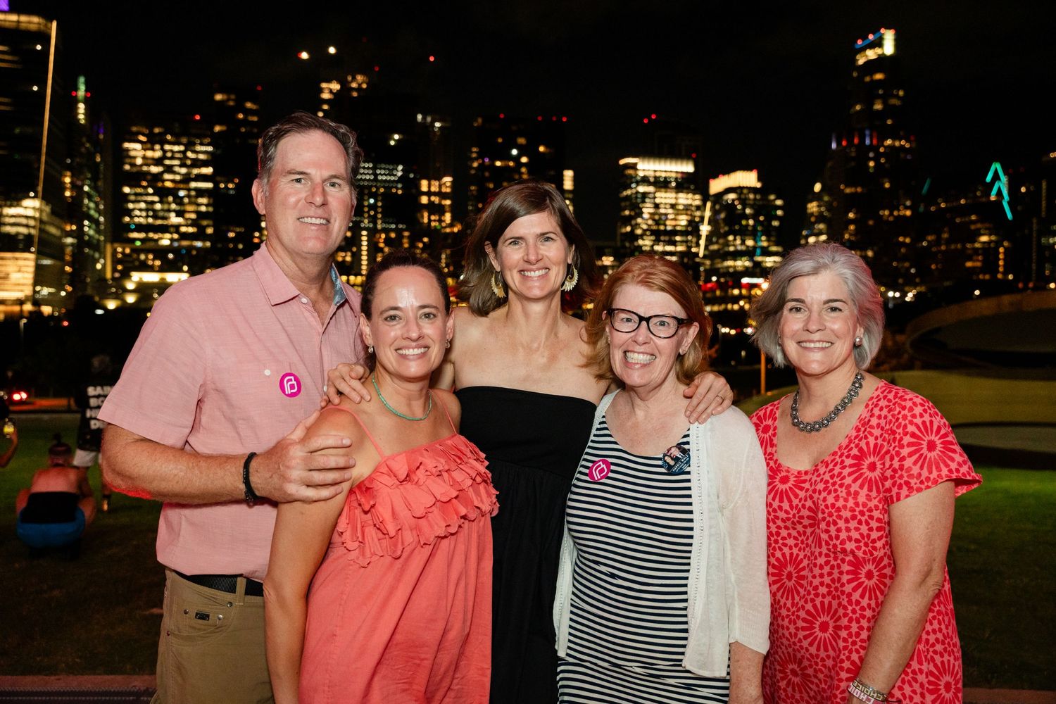 Group photo of event attendees gathered with city lights glowing in the background.