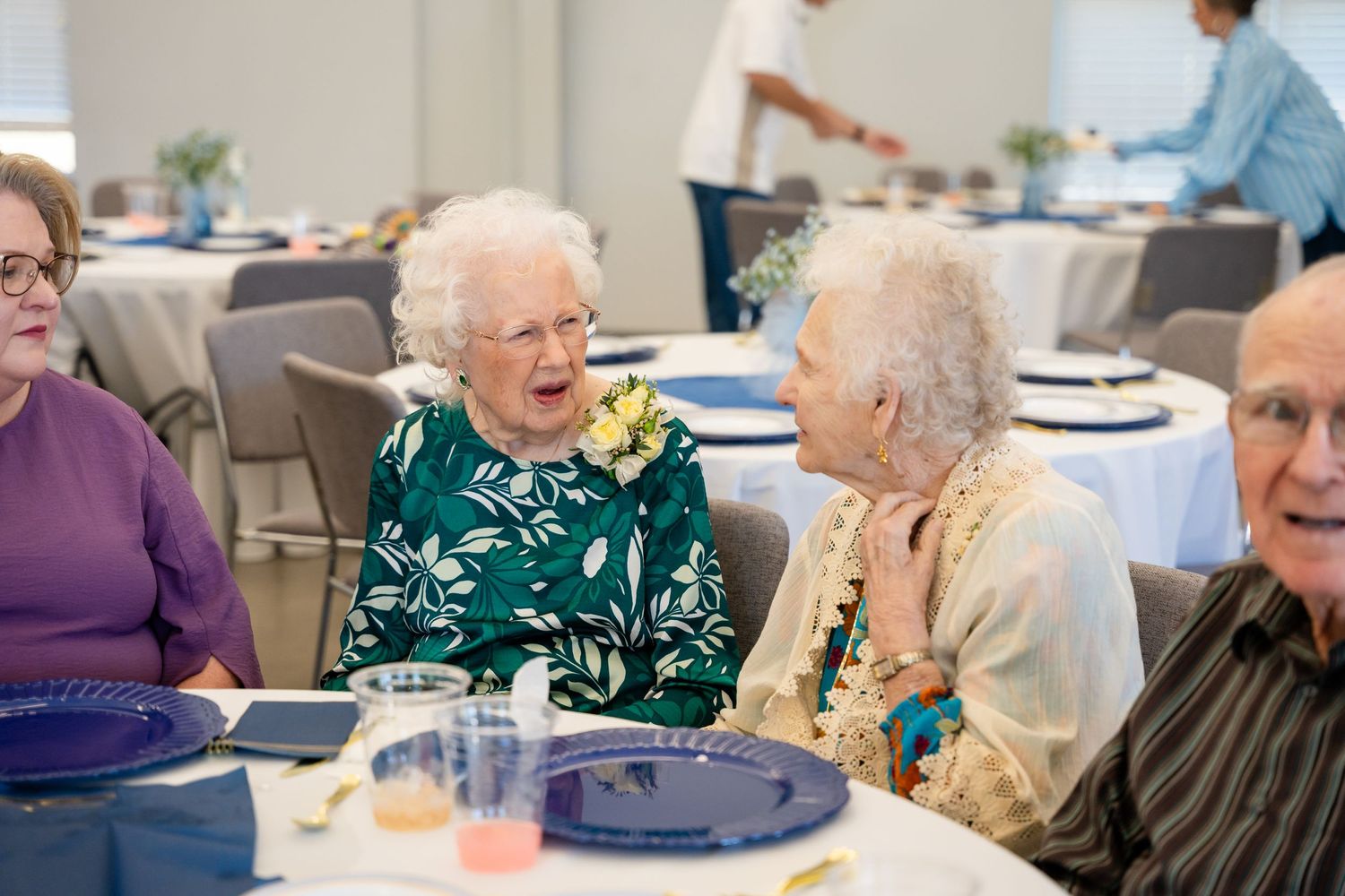 Seniors enjoying conversation and laughter at a social gathering with table settings.
