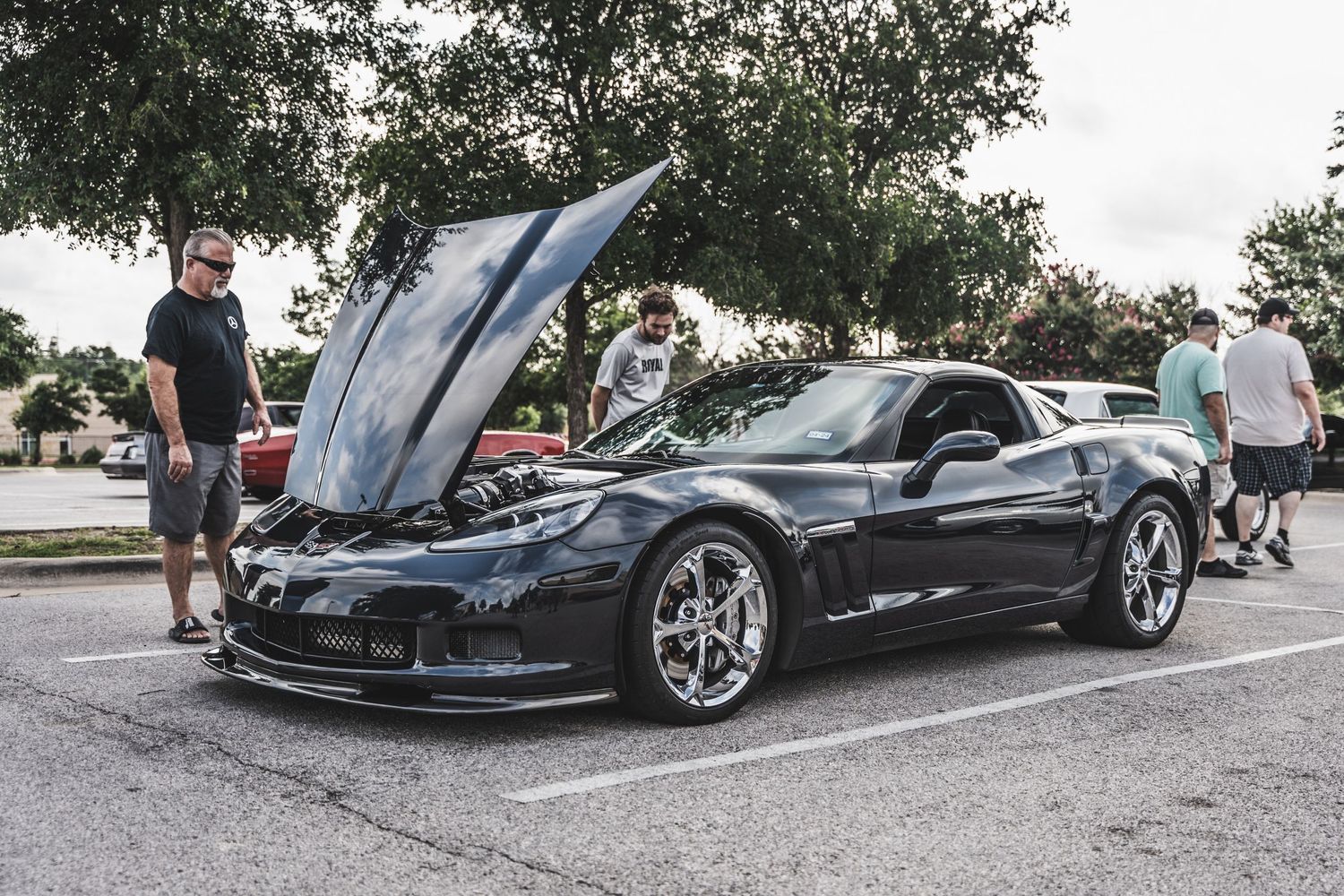 Black Chevrolet Corvette with hood open displayed at a car show.