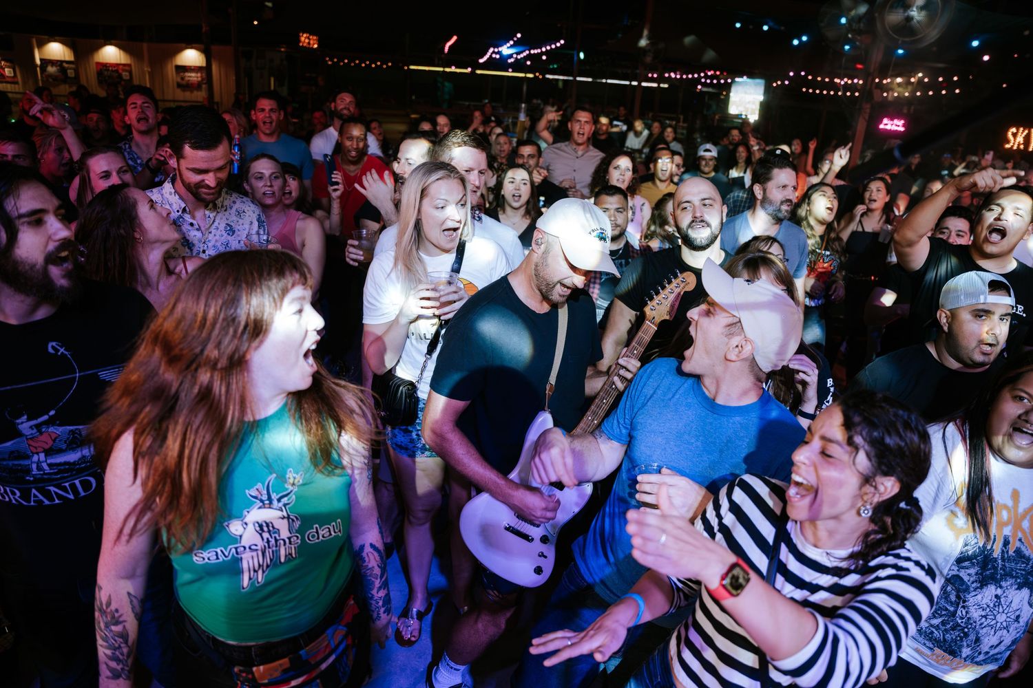 Enthusiastic concert crowd dances and cheers during a high-energy live music performance.