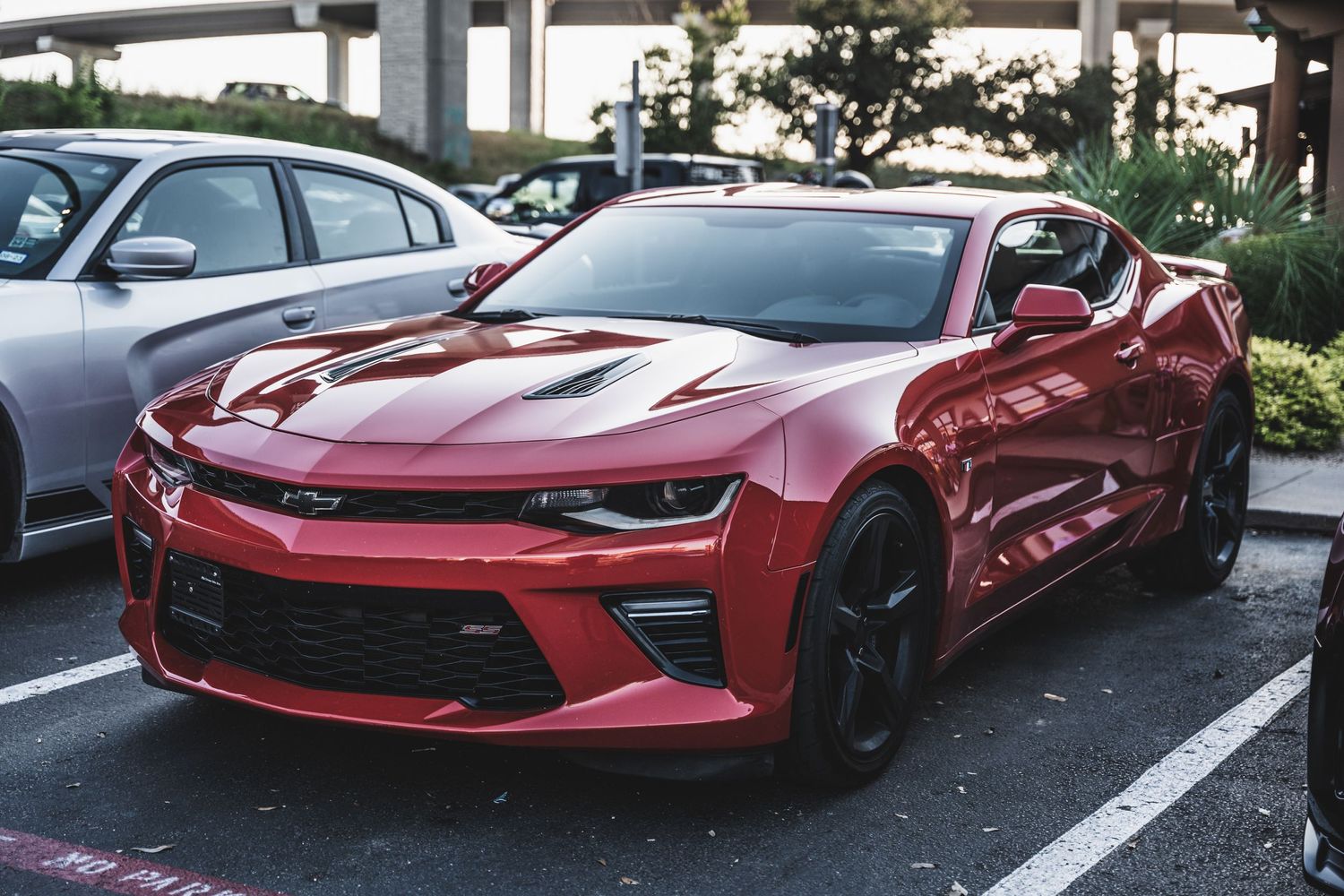 Red Chevrolet Camaro SS with black wheels parked in a shopping center lot.