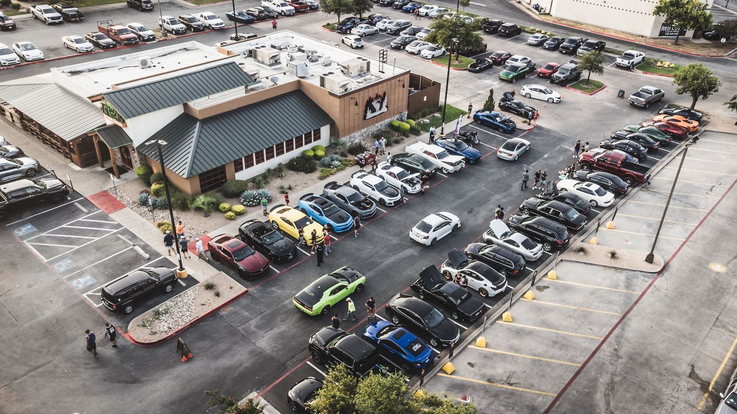 Bird's eye view of a car show at Twin Peaks restaurant with various vehicles filling the parking lot.
