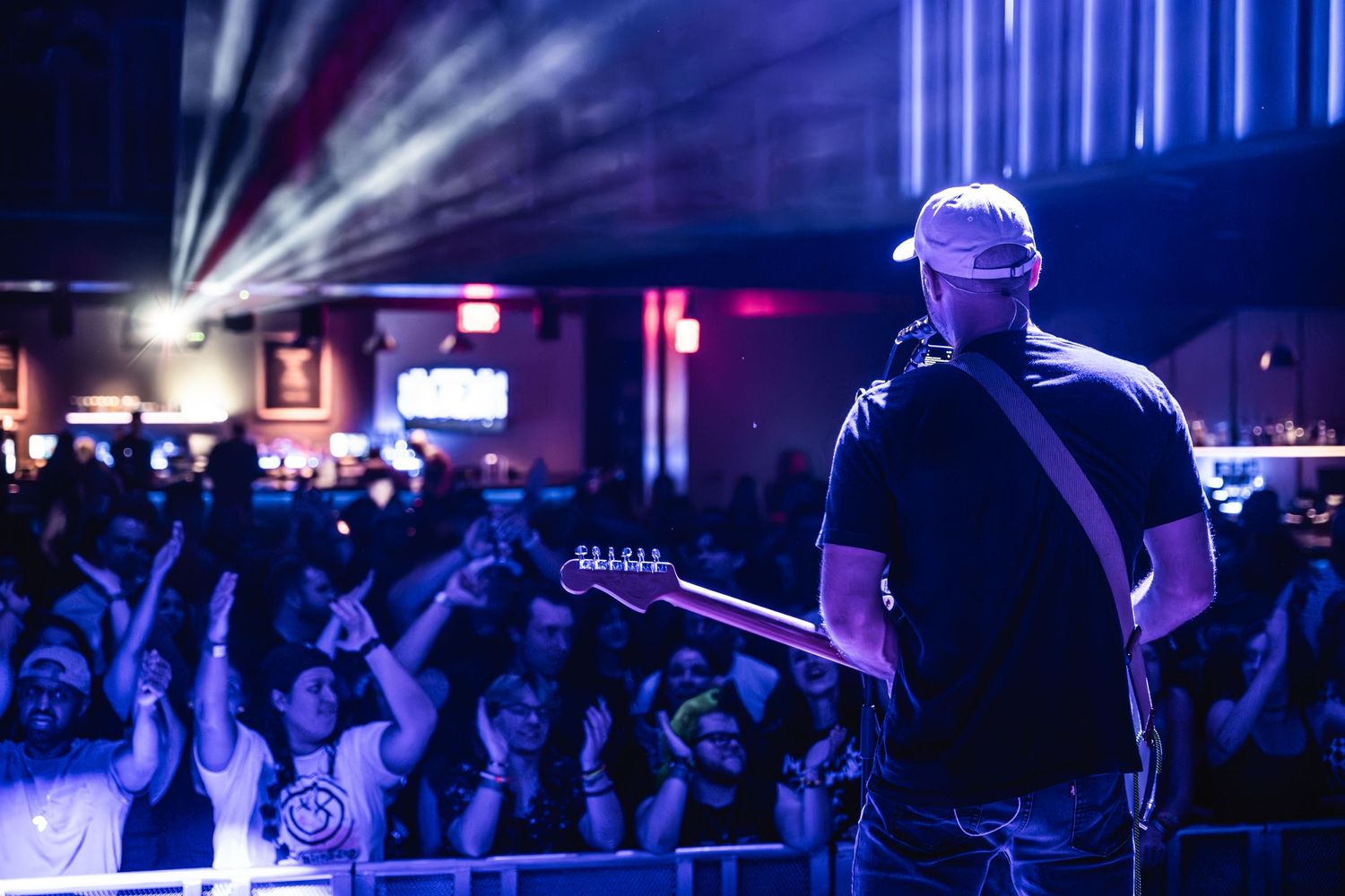 Performer silhouetted against concert crowd and stage lights during live show.
