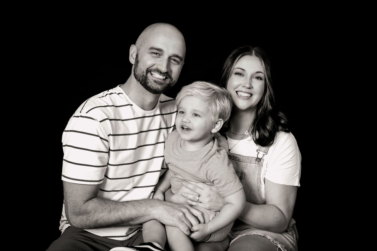 Classic black and white family studio portrait with striped shirt and dark background.