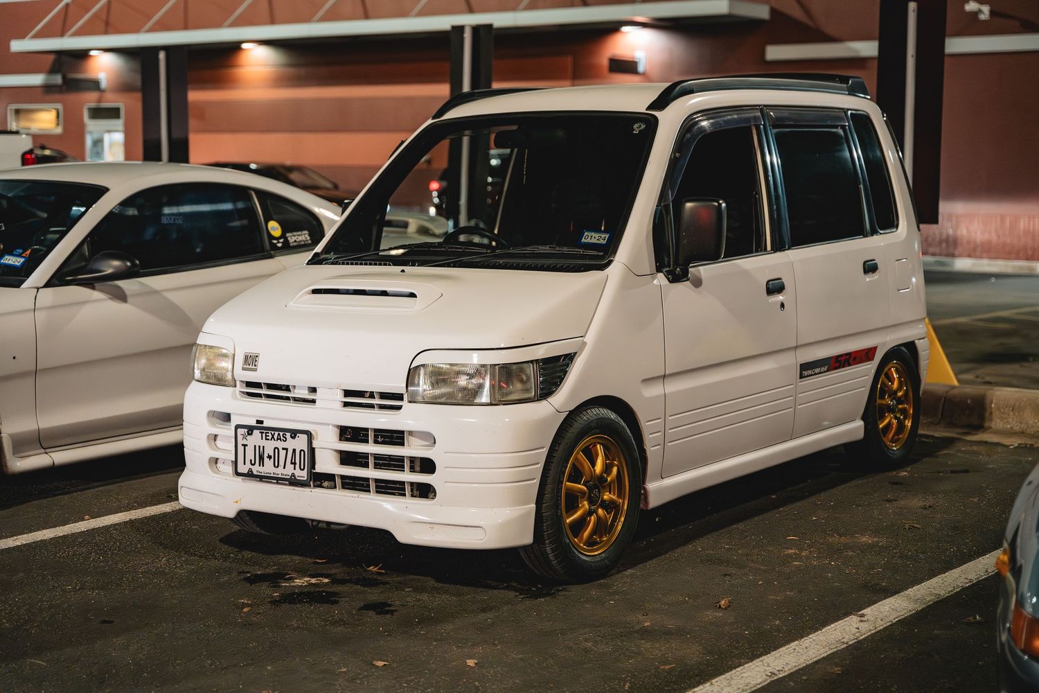 White JDM kei van with gold wheels parked in a lot at night.