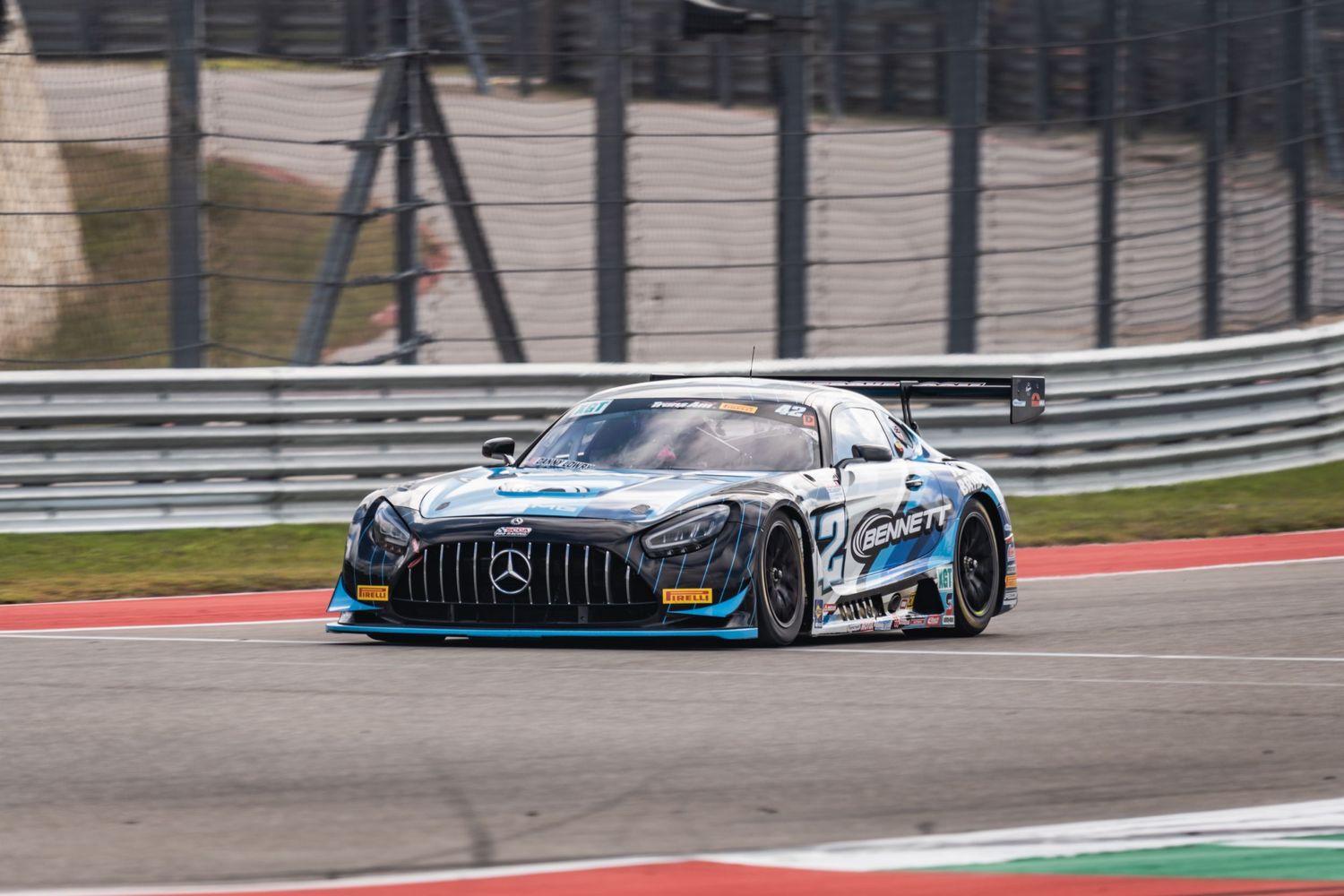 Mercedes AMG GT3 race car speeds through a corner on a professional racing circuit.