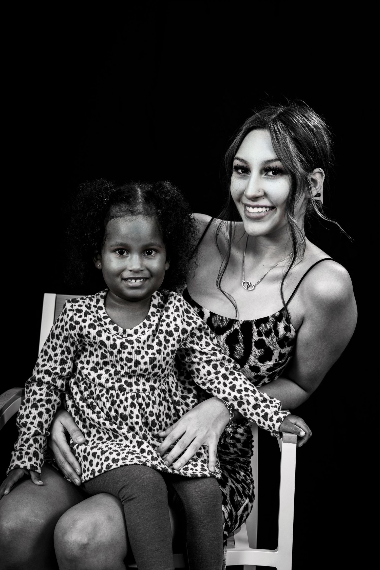 Studio portrait of two people in matching leopard print sitting together.