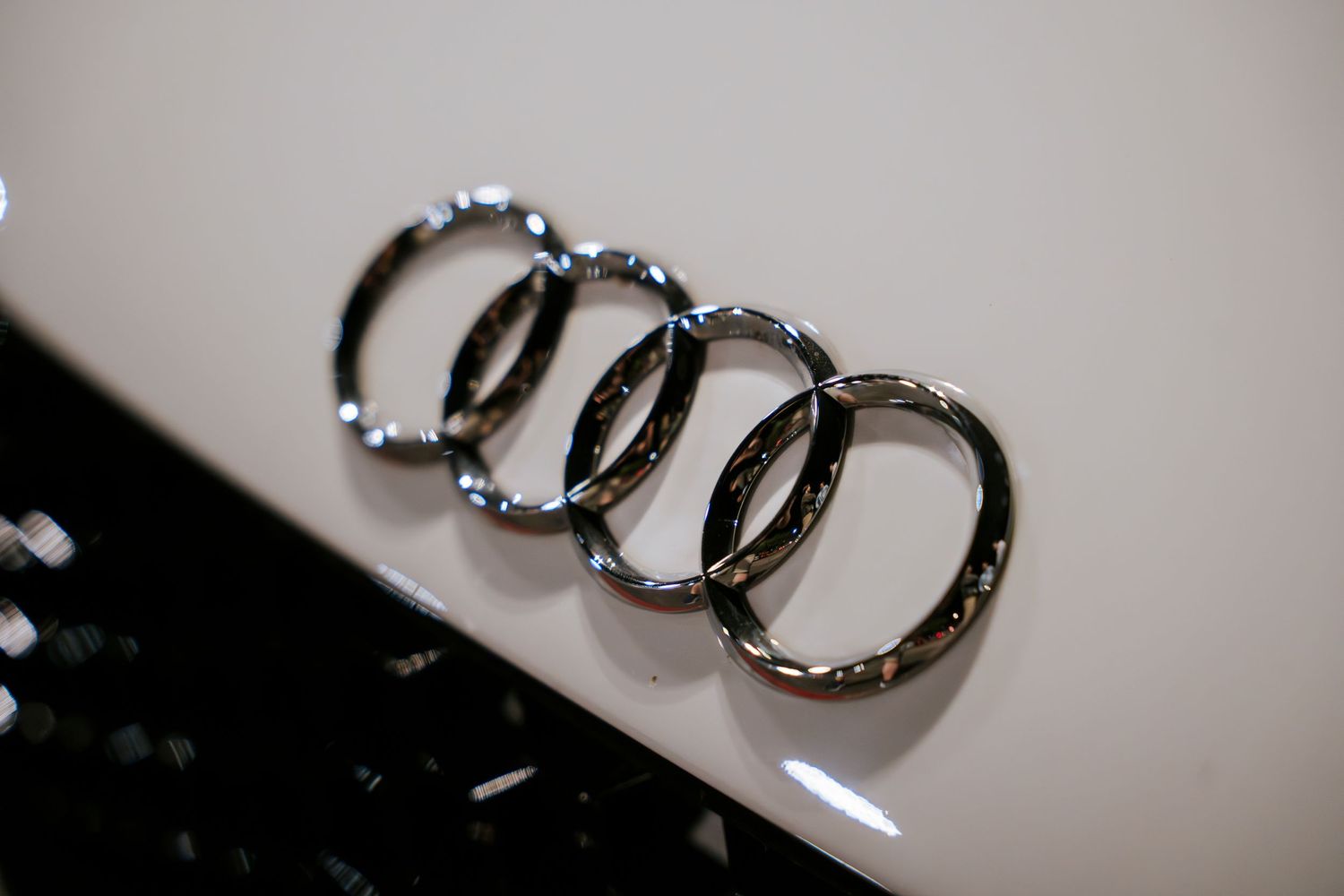 Close-up detail shot of an Audi logo emblem on a white vehicle surface.