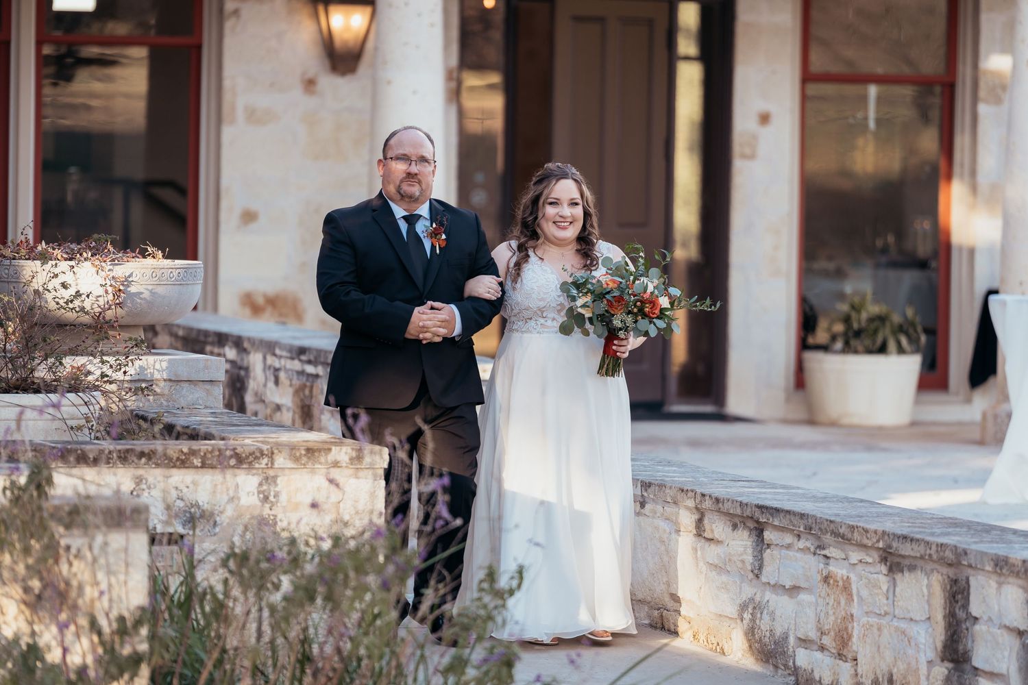 Walking down stone path at outdoor wedding venue during ceremony entrance.