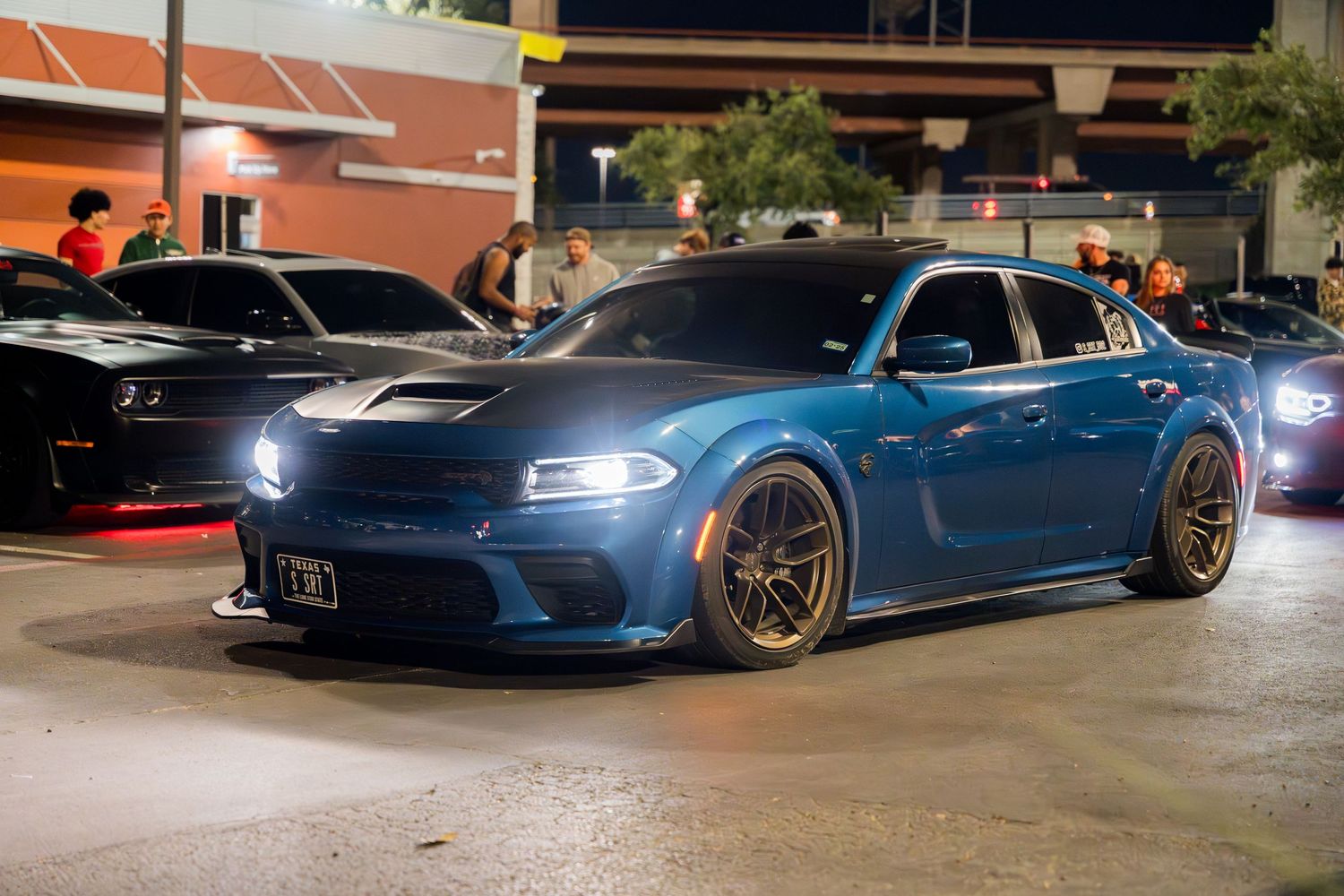 A modified blue Dodge Charger with custom wheels parked at night.