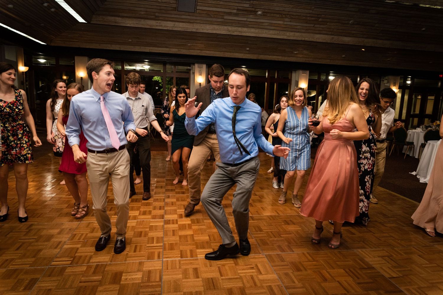 Guests dancing energetically on a parquet floor at a wedding reception.