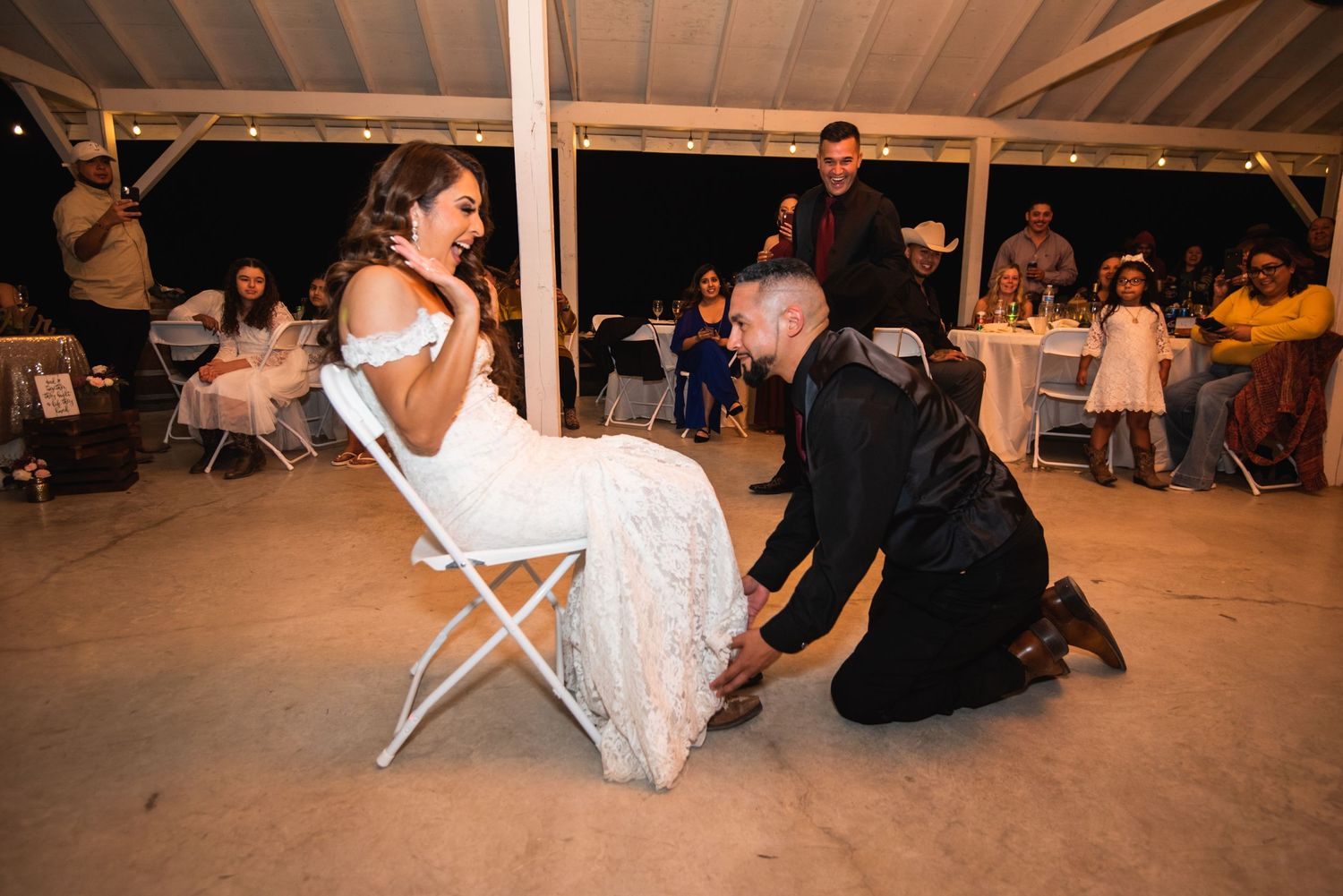 Traditional wedding reception game being played with guests watching in a rustic barn setting.