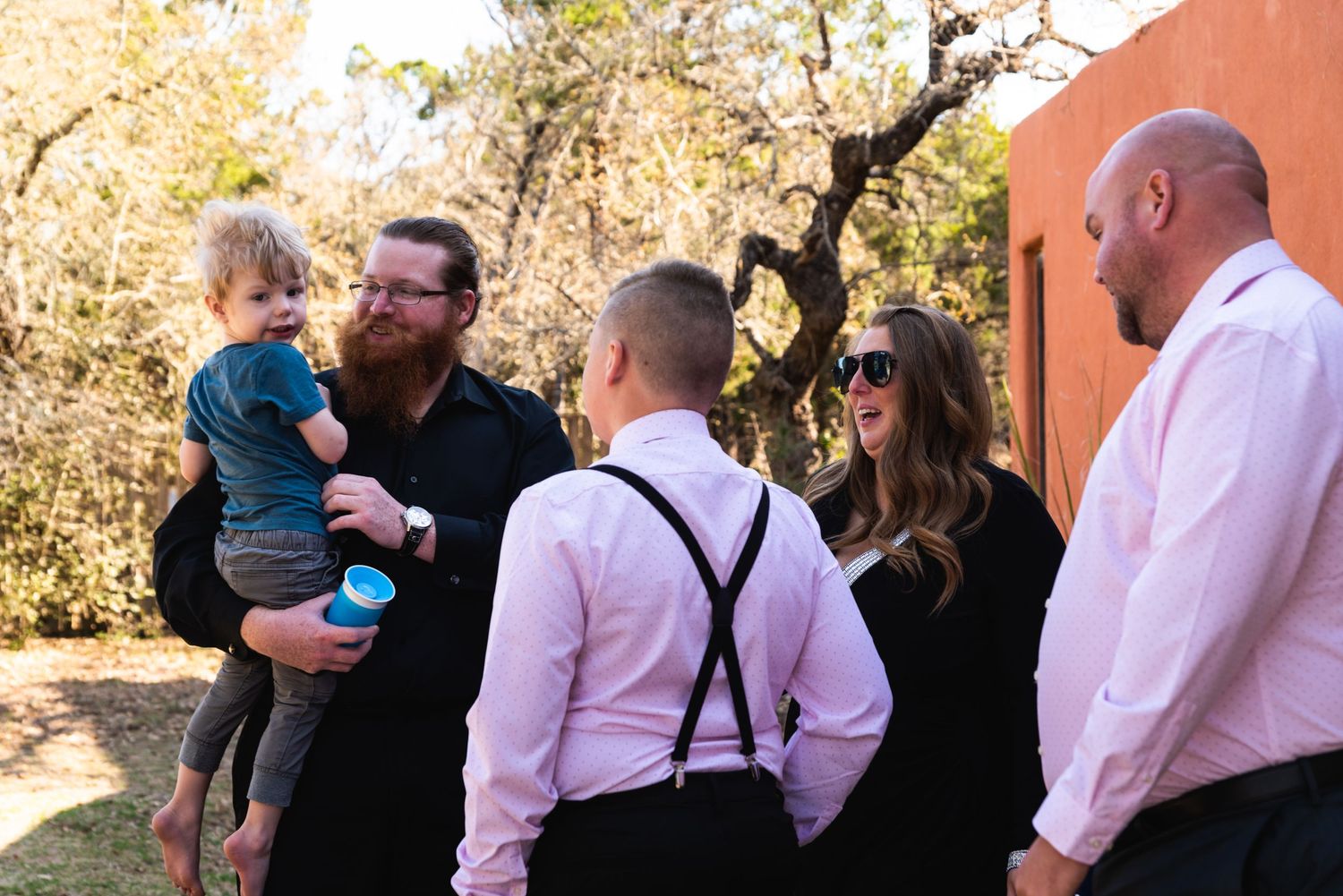 Group of people in formal attire having conversation outdoors.