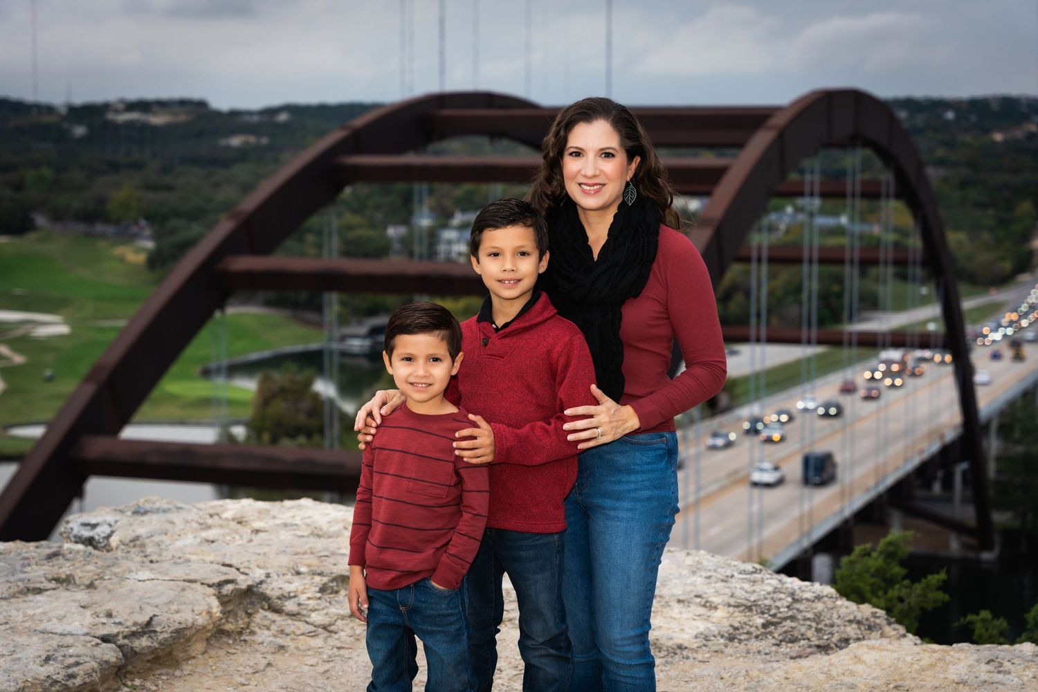 Portrait of three people in coordinated outfits with Pennybacker Bridge in background.