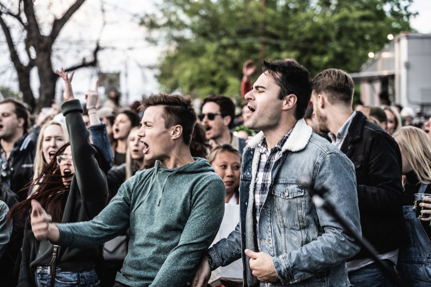 Enthusiastic crowd watching and reacting to performance at outdoor music festival.