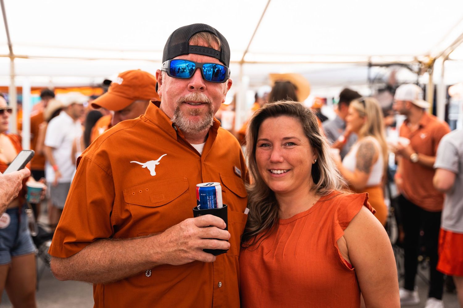 Fans in orange Texas Longhorns gear celebrate at outdoor gathering.