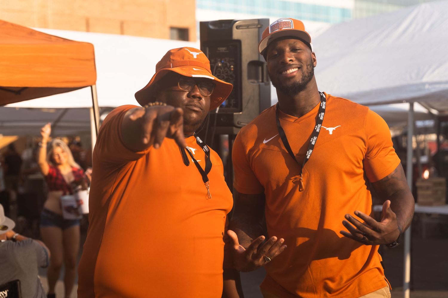 Two event staff members in orange shirts at an outdoor festival setup.