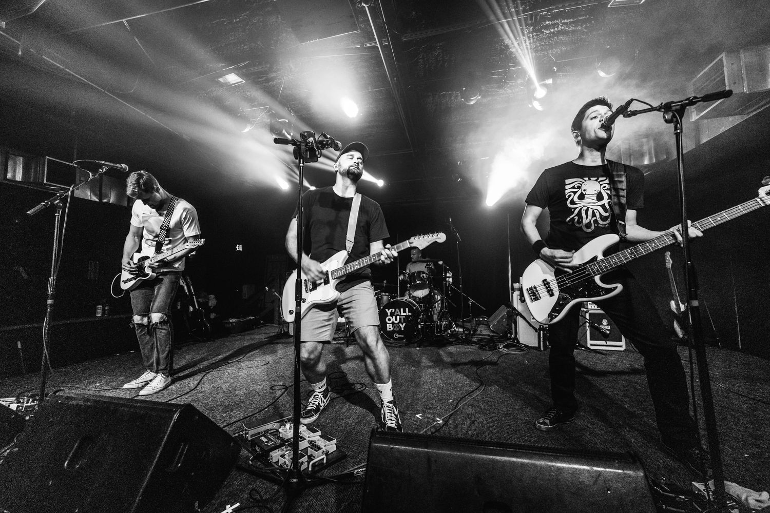 Black and white shot of energetic rock band performing with dramatic stage lighting effects.
