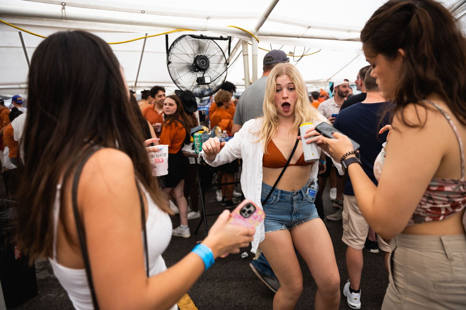 Young people dancing and socializing at a tented outdoor party event.