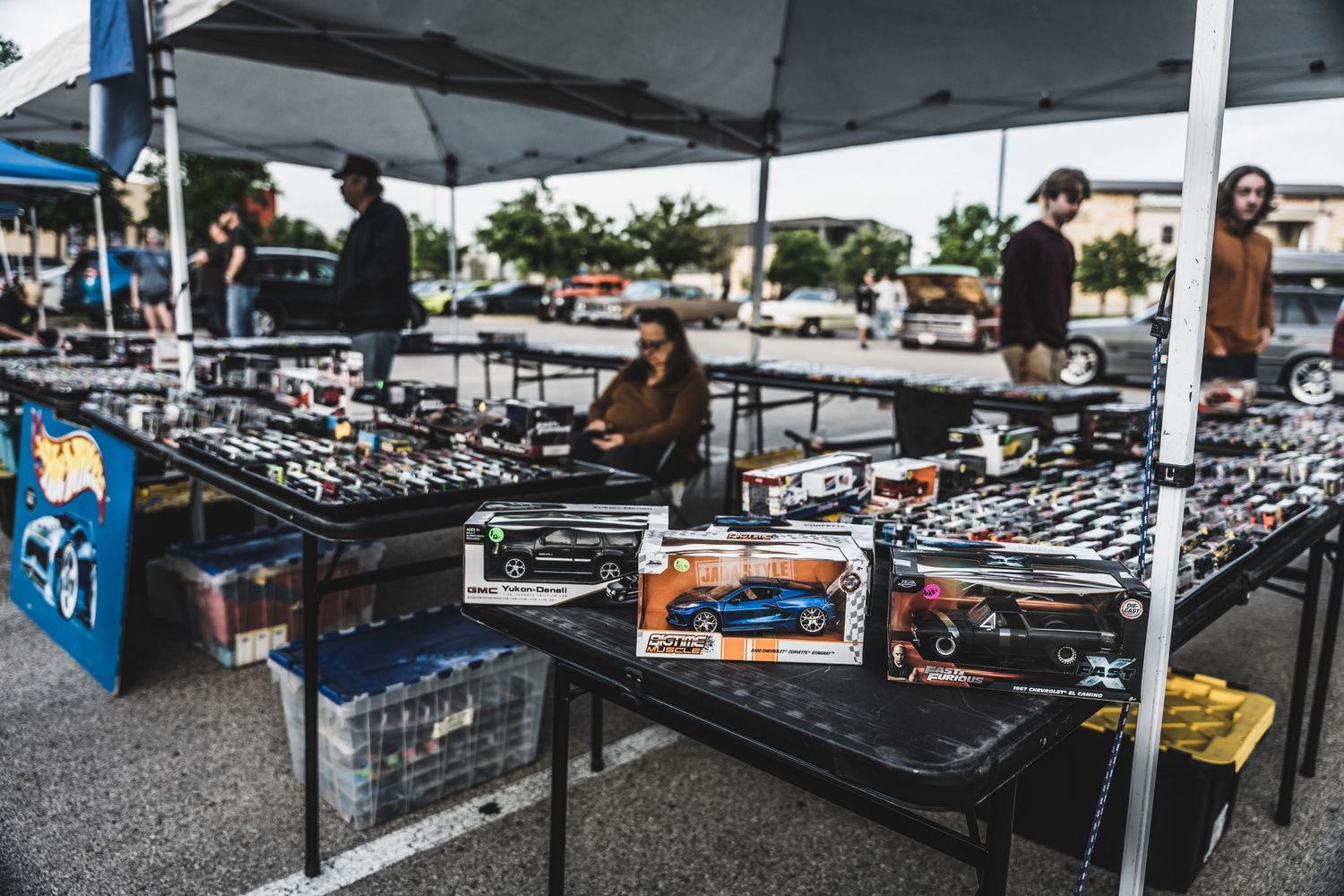 Vendors selling collectible model cars under white canopy tents at outdoor event.