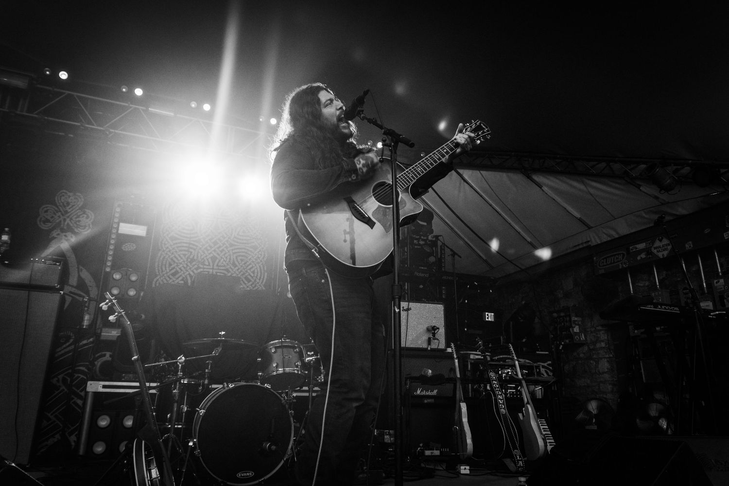 Silhouetted musician performing with acoustic guitar on stage under dramatic lighting.