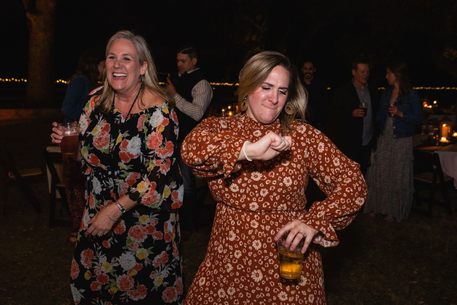 Two guests dancing and having fun at a nighttime outdoor wedding reception.