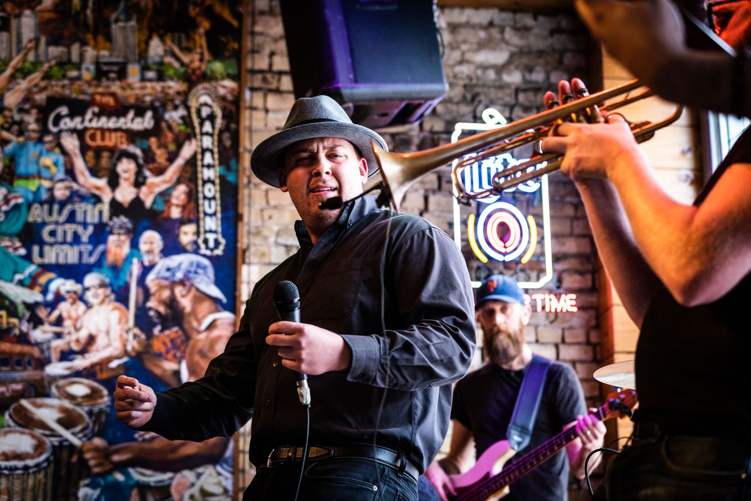 Energetic performance at intimate music venue with brick walls and Miller sign in background.