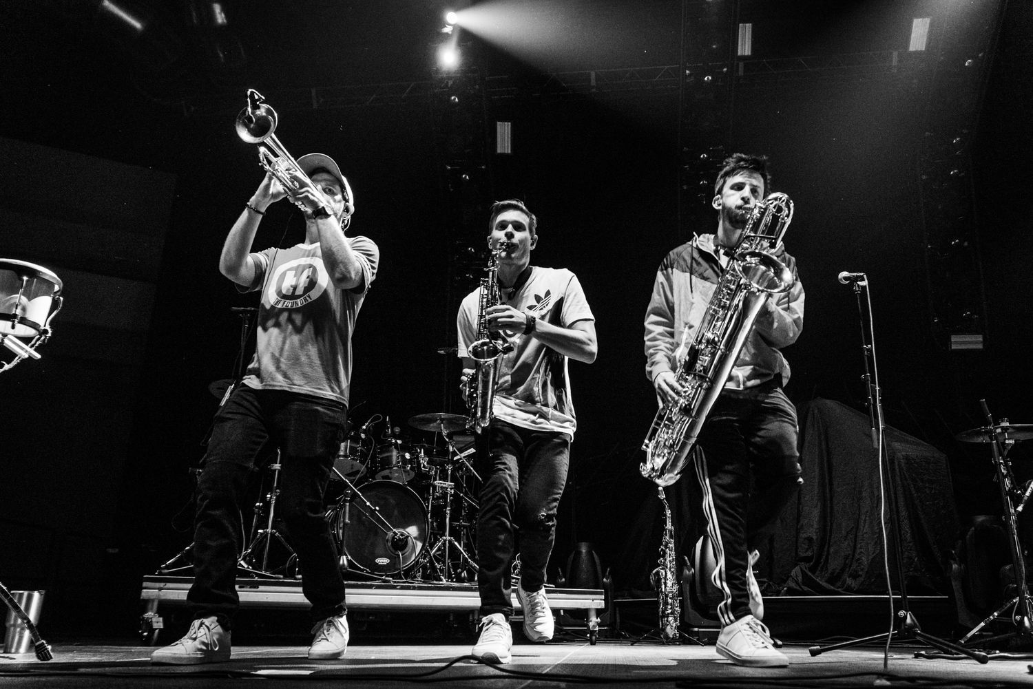 Black and white photo of musicians performing with brass instruments on stage.