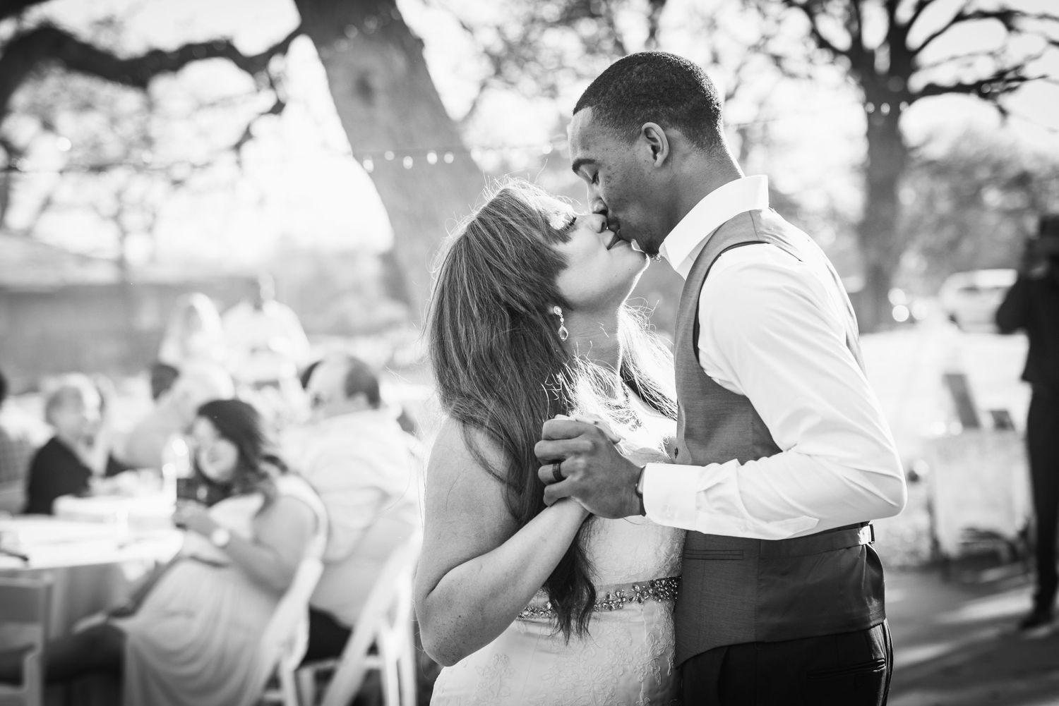 Black and white photo of couple dancing at outdoor wedding reception.