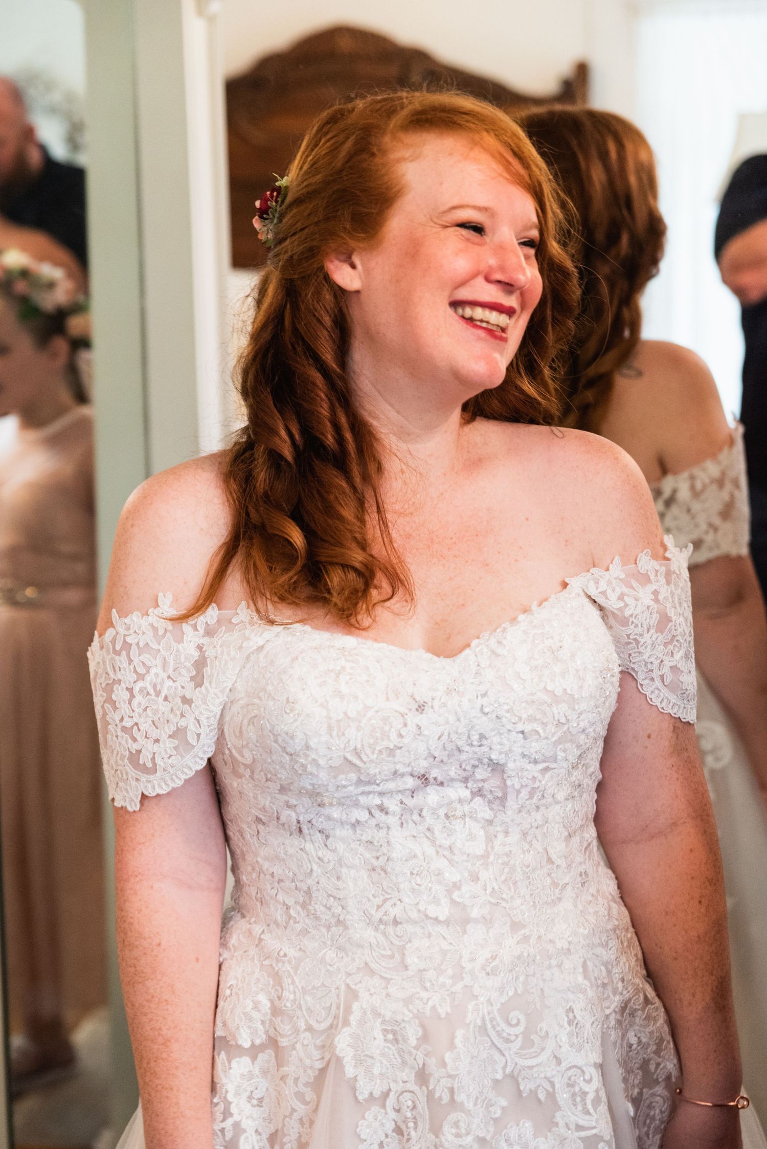 A joyful moment captured during wedding preparations showing a white lace dress.