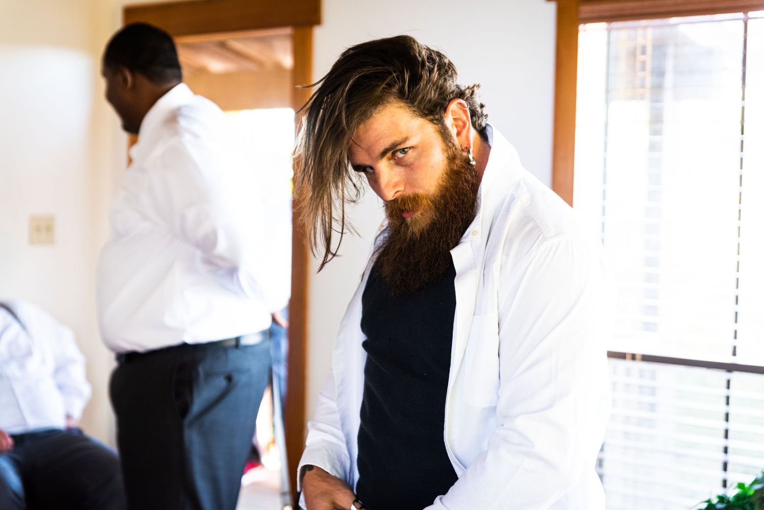 A person in white dress shirt adjusts their appearance in preparation for an event.