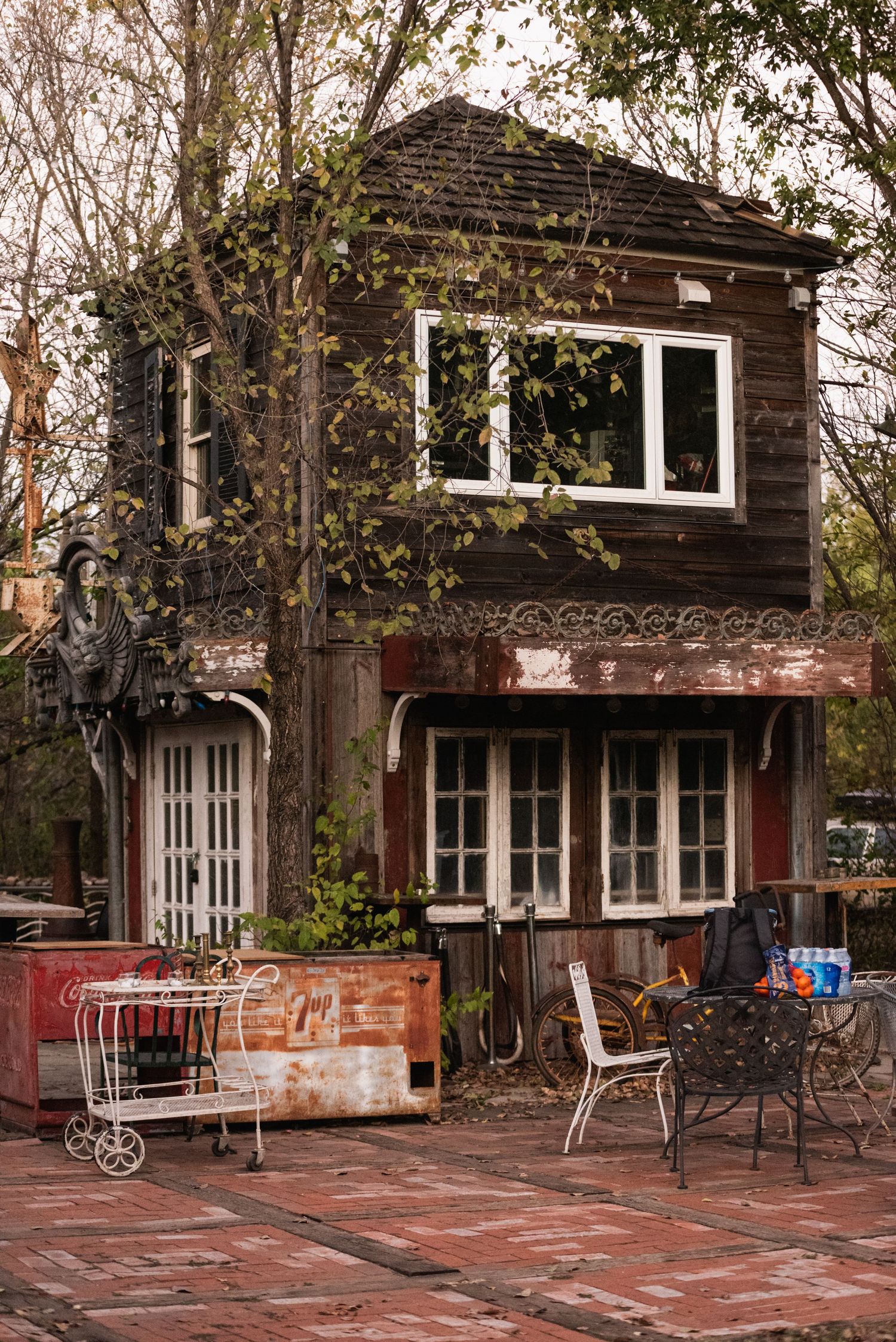 A charming wooden two-story structure with french doors and outdoor seating area on brick patio.