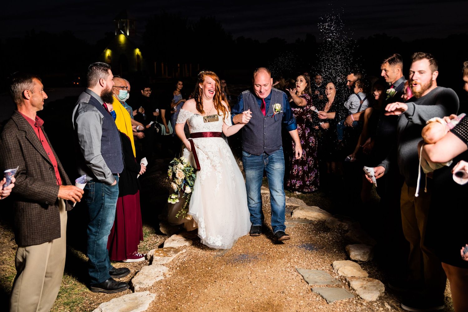 Wedding guests gather in the dark holding sparklers during an evening celebration.