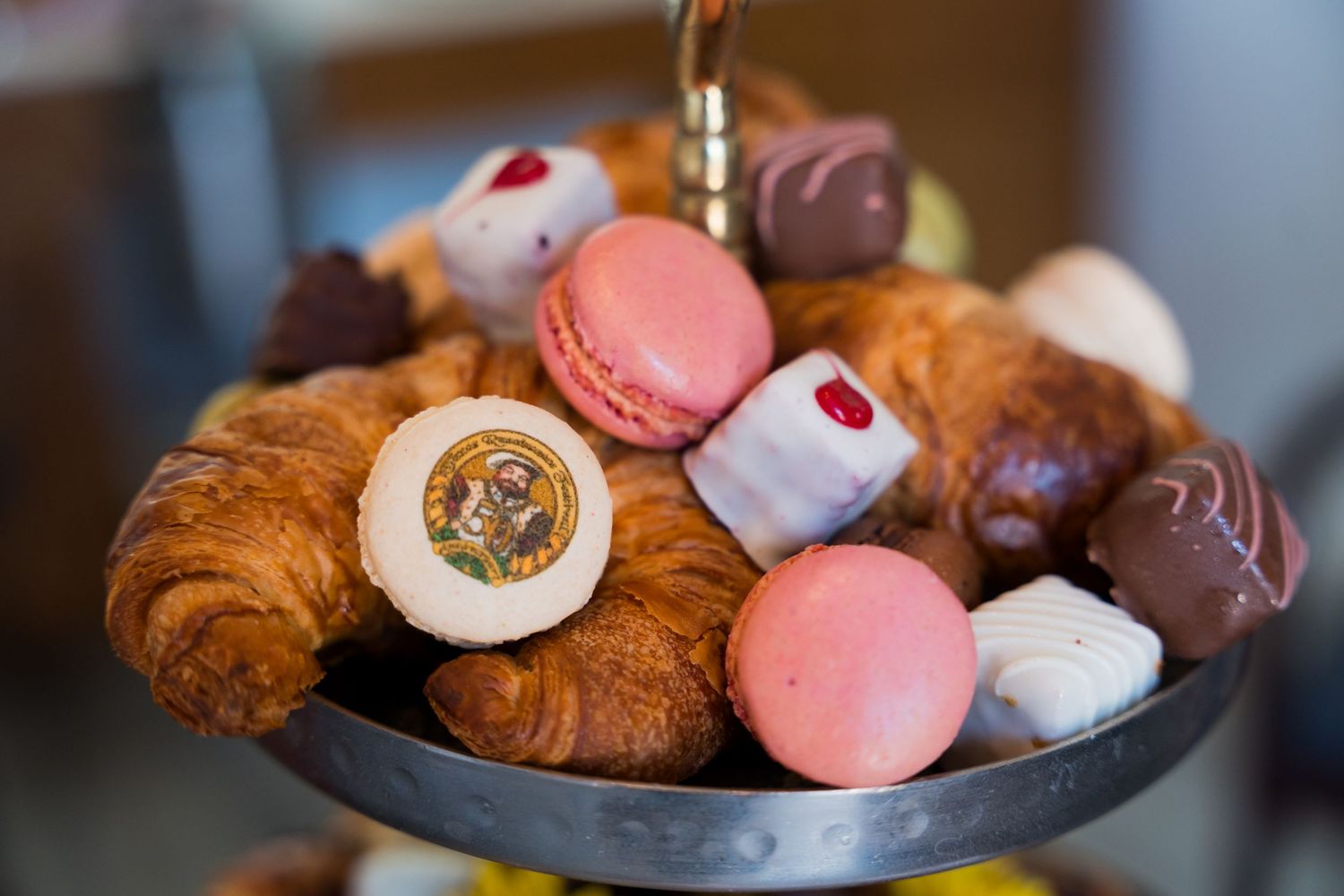 Assorted French macarons and pastries displayed on dark plates with colorful decorative toppings and garnishes.