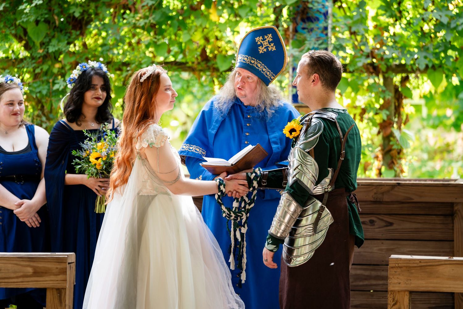 Outdoor wedding ceremony with guests seated on wooden benches surrounded by lush greenery and natural light.