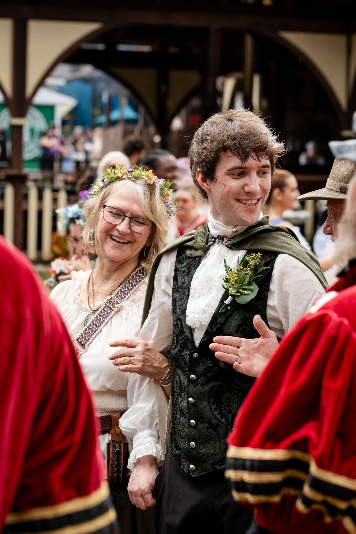 People dancing and smiling at a traditional folk dance event wearing period costumes.