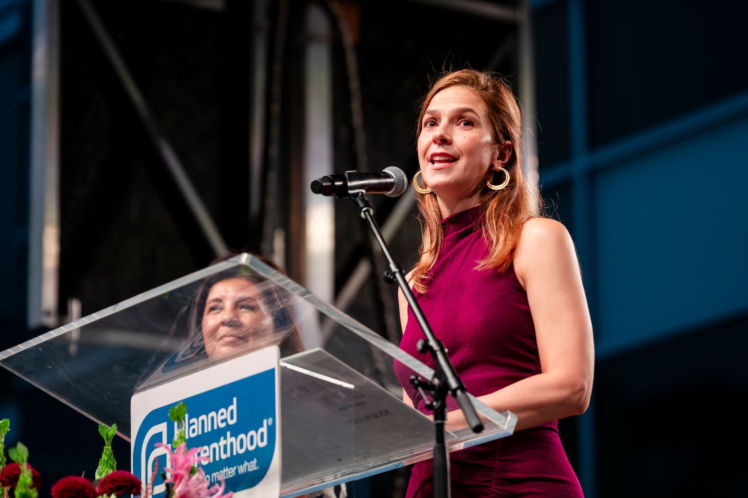 A speaker stands at a podium with Planned Parenthood signage visible during a public event.