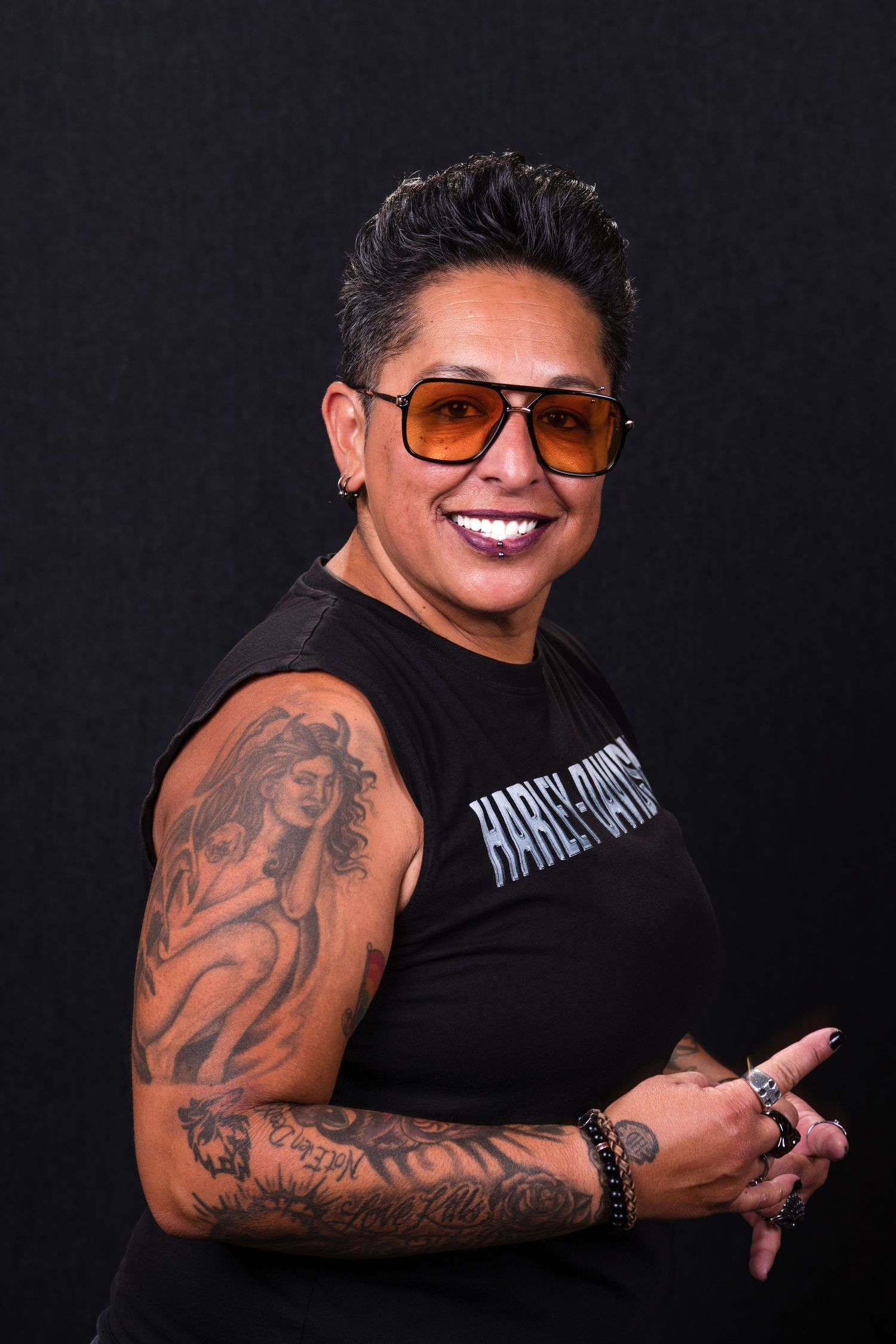 A series of black and white photos showing someone in a black t-shirt displaying arm tattoos against a dark background.