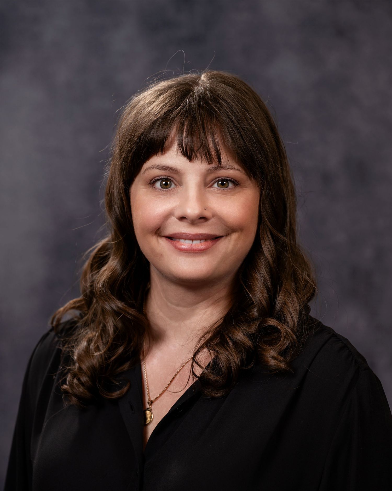 Professional headshot portraits showing different expressions and poses against a dark gray backdrop.