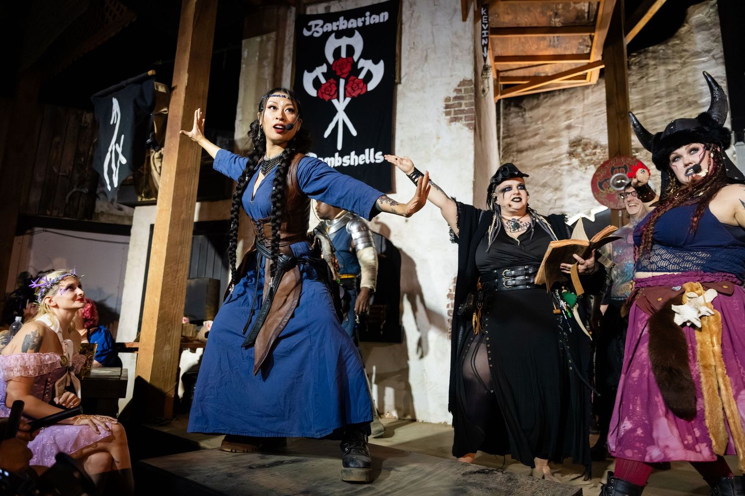 Performers in period costumes act out dramatic scenes on stage during a theatrical production.