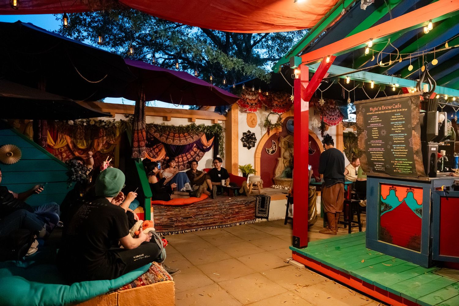 Colorful carnival game booths and attractions line a festive outdoor entertainment area at night.